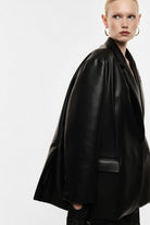 Blazer oversize en cuir synthétique porté de profil – Noir – Imperial Femme